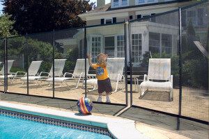 Small kid by fence of pool